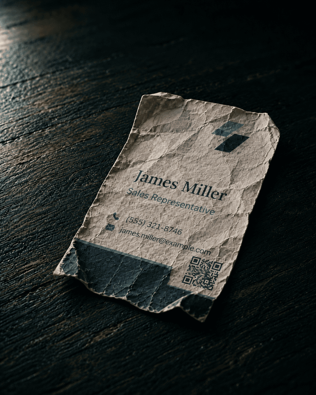 A crumpled business card on a dark wooden desk
